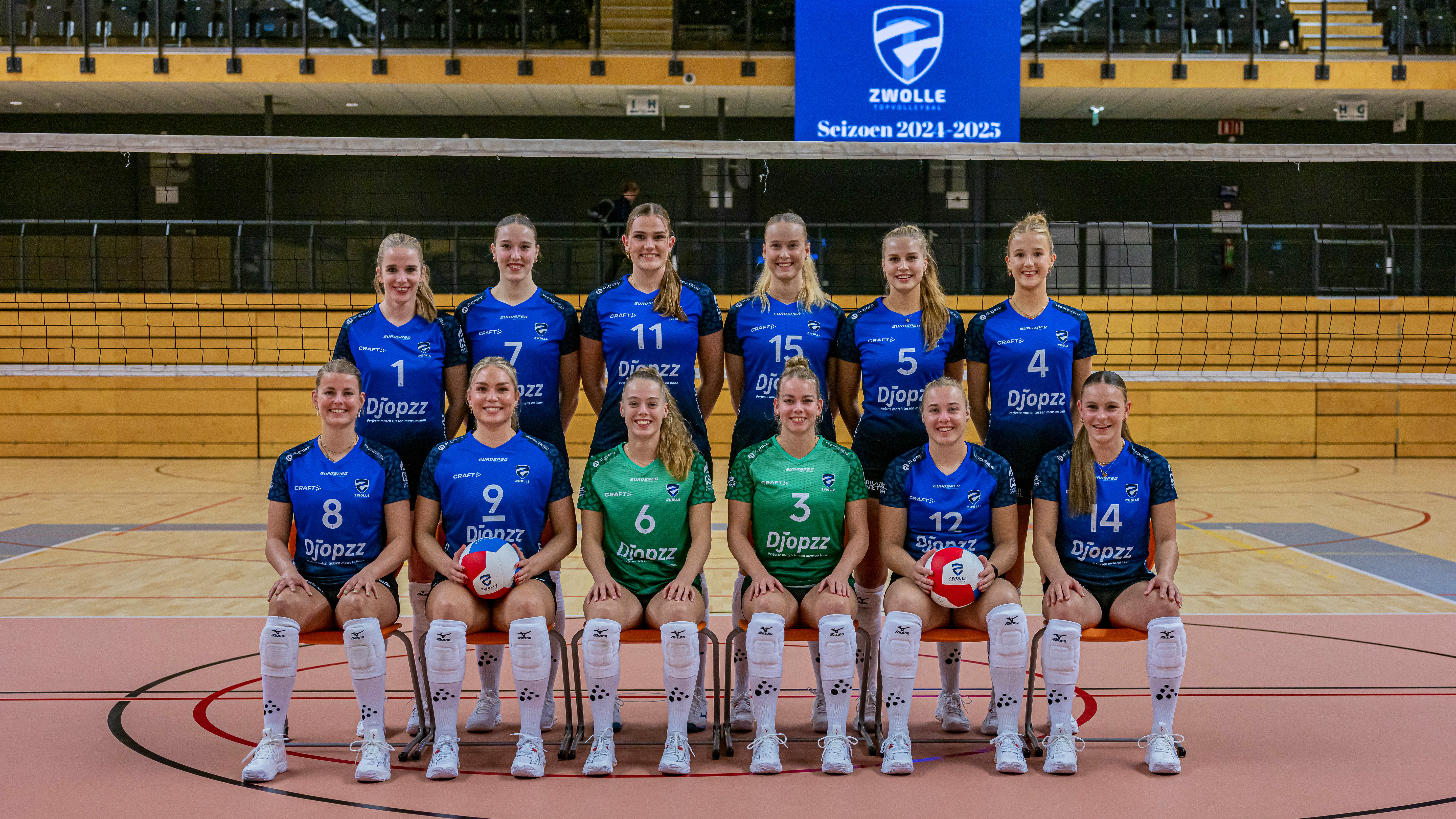 Het volledige team van Topvolleybal Zwolle. In het midden, verdeelt over twee rijen, staan de volleyspelers in het blauw. Ze staan in hun thuiszaal in het Landstede Sportcentrum.